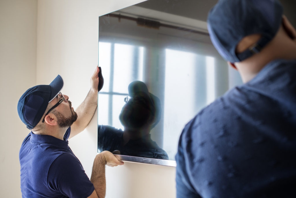 Two installers mounting a large flat-screen television on a wall